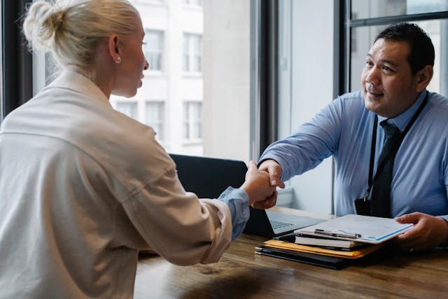 two-people-having-a-business-meeting-shaking-hands-over-a-desk