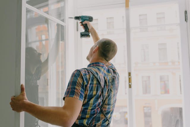 A person drilling the side of the window